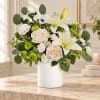 White lilies and cream roses in a white vase with green accents