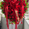 Heart-shaped standing spray of red carnations with ribbon