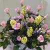 Pink roses and lavender flowers arranged in a white basket