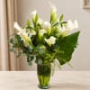 White calla lilies and roses arranged in a glass vase