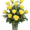 Yellow roses arranged in a clear glass vase with greenery