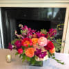 Colorful mixed flower arrangement in a square glass vase on a table