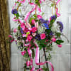 Tall floral spray with pink roses, lilies, and purple accents on a stand
