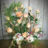 Tall arrangement of peach roses, white flowers, and pink ribbons