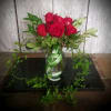 Red roses in a clear glass vase with trailing greenery
