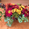 Low floral arrangement with magenta and yellow daisies on a table
