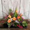Low floral arrangement with orange roses and tulips in a black container
