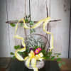 Basket arrangement with pink flowers, greenery, and yellow ribbon on a twig frame