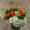 Bouquet of orange and red roses with white blooms in a square glass vase