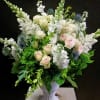 White and blush bouquet in a white pedestal vase