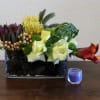 Mixed floral arrangement in a glass vase with a small blue candle beside it