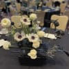 Modern floral centerpiece with white blooms and dark spiky accents in a black vase