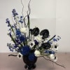 Blue and white floral arrangement in a black vase with tall curly branches