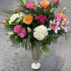 Mixed bouquet of pink and orange roses with lilies in a tall vase