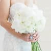 Bride holding a white wedding bouquet with a photo charm