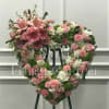Heart-shaped floral wreath with pink and white flowers on an easel