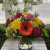 Mixed bouquet in a clear glass vase with bright gerbera daisies and roses