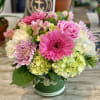 Pink and lavender flowers arranged in a green hatbox