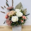 Bouquet of white and blush flowers in a square vase with dried grasses