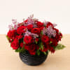 Fragrant lilac peeking through luxurious red roses, spray roses, and ranunculus designed