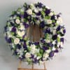 Round floral wreath with white, purple, and green flowers on an easel