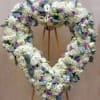 Heart-shaped floral wreath of white blooms and lavender roses on a stand