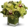 Green floral arrangement with orchids, roses, and hydrangea in a glass cube vase