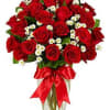 Bouquet of red roses with small white filler flowers in a glass vase