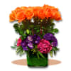 Orange roses and purple flowers in a green glass vase