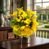 Yellow calla lilies and roses arranged in a silver vase