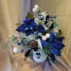 Blue floral arrangement with ornaments in a white vase