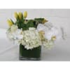White orchids and hydrangeas with yellow tulips in a glass vase