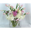 Pink tulips and white flowers arranged in a clear square vase with a pink ribbon