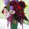 Mixed bouquet in a clear glass vase with purple, red, and white flowers