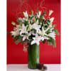 White lilies in a tall glass vase with pine accents