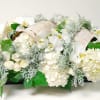 White floral arrangement with orchids and hydrangeas in a low container