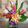 Tropical flower arrangement with orchids, calla lilies, and pink ginger in a glass vase
