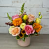 Mixed bouquet in a blush vase with pink, peach, yellow, and orange blooms