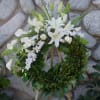 White floral wreath on a stand with lilies, calla lilies, and orchids
