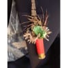 Small boutonniere with green leaves and dried grasses on a red shell casing