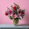 Mixed bouquet of red, pink, and white flowers in a clear glass vase