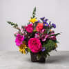 Mixed bouquet of bright roses, daisies, and lilies in a dark vase