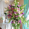 Large pink and purple floral arrangement on a stand