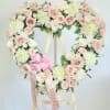 Heart-shaped floral wreath of pink and white roses on a wooden easel