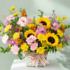 Basket arrangement with sunflowers, pink blooms, and a striped ribbon