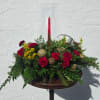 Red carnations and yellow filler in a glass hurricane vase with a red candle