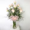 Bouquet of pale pink roses in a clear glass vase with a pink ribbon