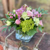 Pink and green floral arrangement in a square glass vase