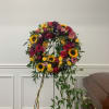 Large standing circular wreath on a metal easel with sunflowers, roses, carnations