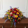 Large cascading casket spray with red roses, mixed daisies, carnations and colorful